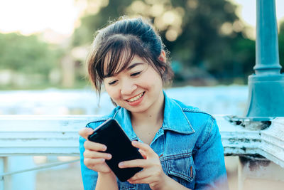 Portrait of smiling young woman using mobile phone