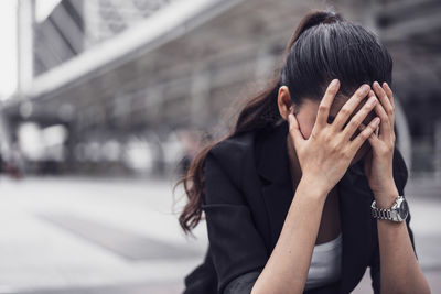 Tensed businesswoman sitting on street in city