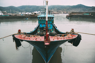 Fishing boat moored in lake against sky