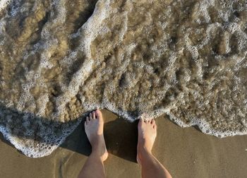 Bare feet of a woman on the beach and waves