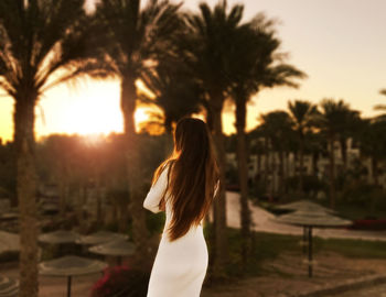 Rear view of woman standing at sunset