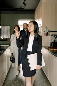 Realtor pointing while showing kitchen area to customers at new house