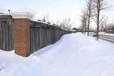 Snow covered houses by building against sky