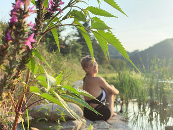 Portrait of beautiful woman sitting by lake during sunny day