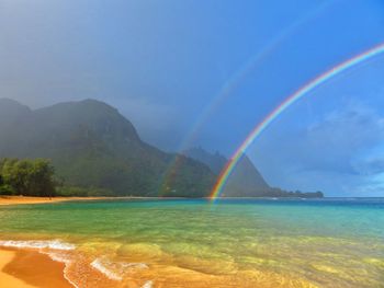 Scenic view of rainbow over sea against sky