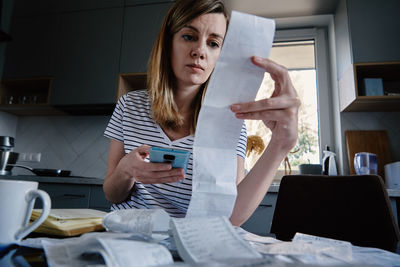 Woman looking at paper bill and counting expenses
