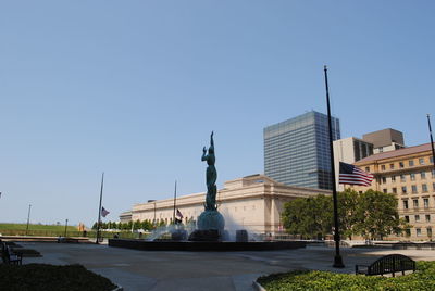 Statue in city against clear blue sky