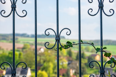 Close-up of metal gate against sky