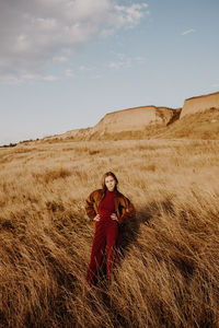 Portrait of woman standing on field against sky