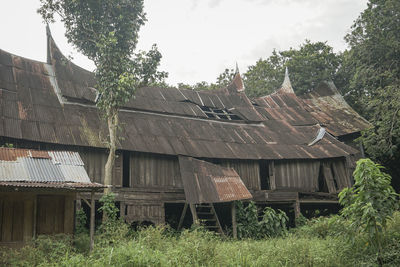 Old building by trees on field against sky