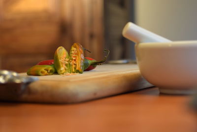 Green and red chili peppers on cutting board in kitchen