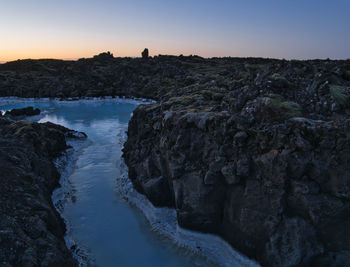 Scenic view of rocks against clear sky during sunset