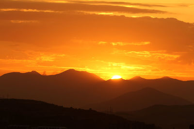 Scenic view of silhouette mountains against romantic sky at sunset