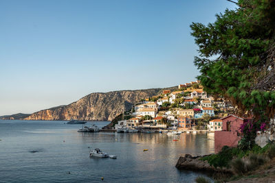 Buildings by sea against clear sky