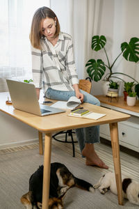 Young woman working on laptop at home. cozy home office workplace, remote work, e-learning concept.