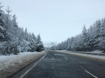 Road passing along snow covered forest