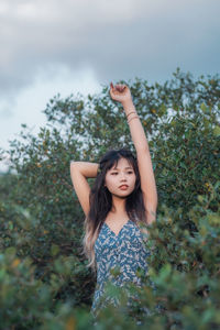 Portrait of young woman standing against trees