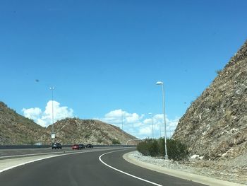 Road by mountain against clear blue sky