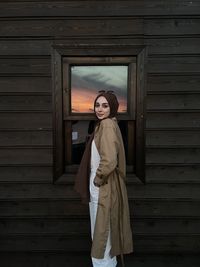 Portrait of woman standing by wall