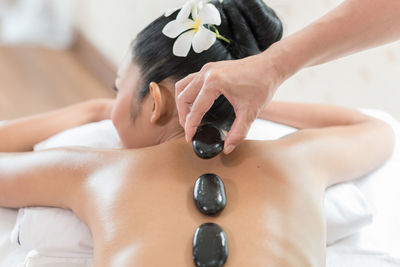 Cropped image of therapist placing hot stones on woman back