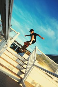 Low angle view of boy jumping while skateboarding against sky