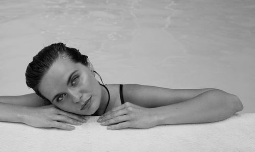 Portrait of young woman leaning at swimming pool