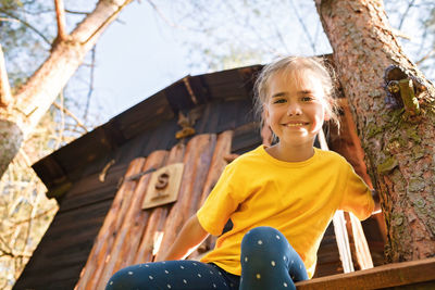 Girl plays in creative handmade treehouse in backyard, summer activity, happy childhood, cottagecore