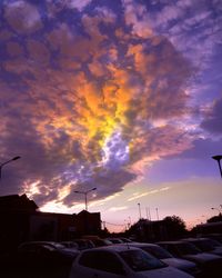 Vehicles on road against cloudy sky during sunset