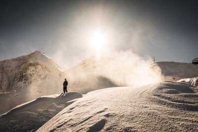 Man standing on snowcapped mountain against sky
