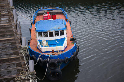 Old fishing boat docking at the pier. vibrant orange and blue. rusty.