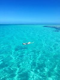 Woman swimming in blue sea against clear sky