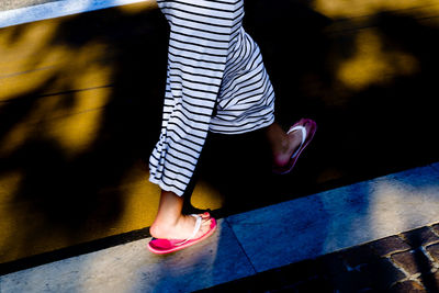 Low section of woman walking on footpath