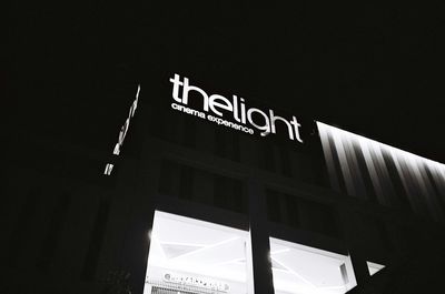 Low angle view of information sign against sky at night