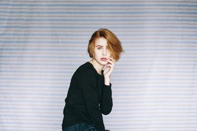 Portrait of woman standing against wall