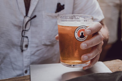 Midsection of woman drinking glass on table