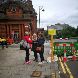 People standing on street in city against sky