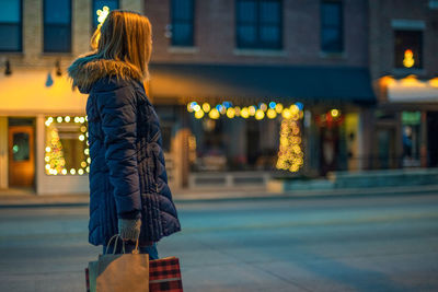 Rear view of woman walking on street at night