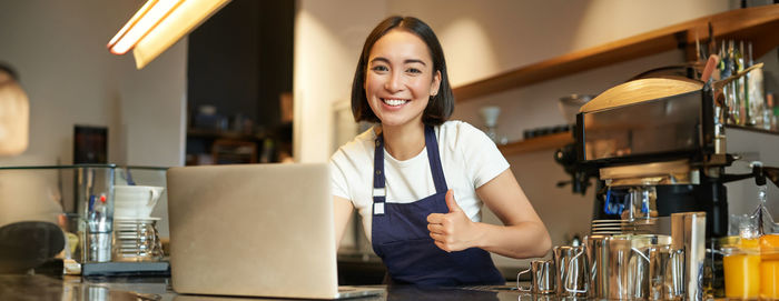 Portrait of young woman using mobile phone while sitting on table