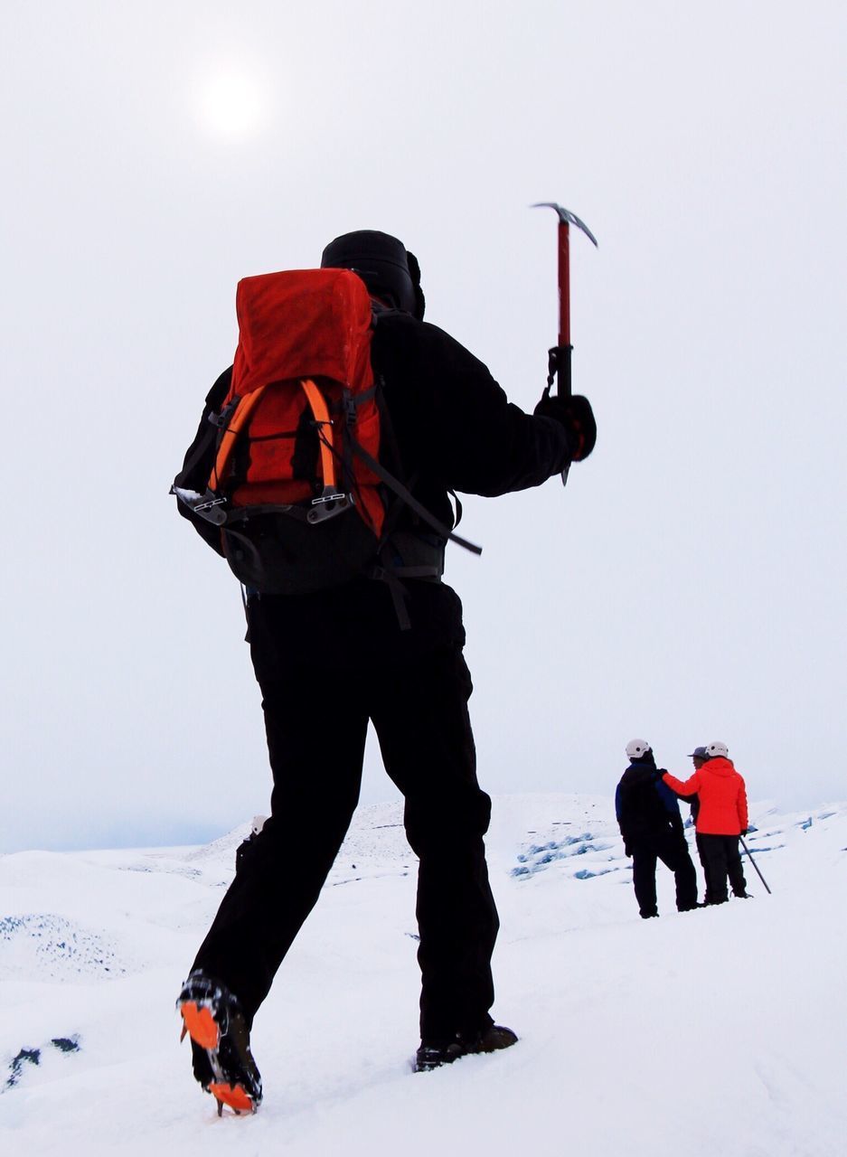People standing on snowcapped mountain against clear sky
