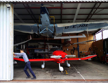 Rear view of man standing by airplane at airport