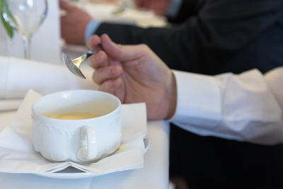 Cropped hands of man with soup on table in restaurant