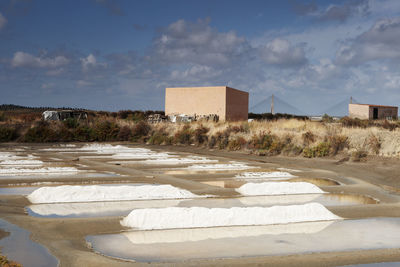 Snow covered land by building against sky