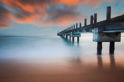 Pier over sea against sky during sunset