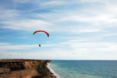 People paragliding over sea against sky