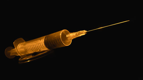 Close-up of hand holding light bulb over black background
