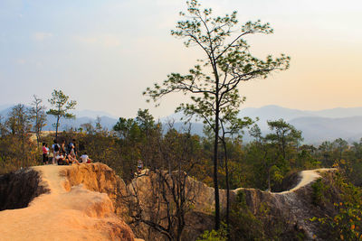 People on rock against sky