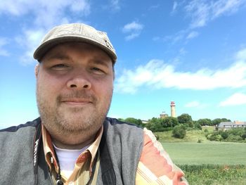 Portrait of man wearing cap on field against sky