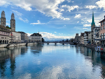 Buildings at waterfront against cloudy sky