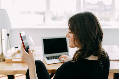 Business girl freelancer in casual clothes works using wireless technology in the home office