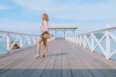Full length of woman standing on pier over sea against sky